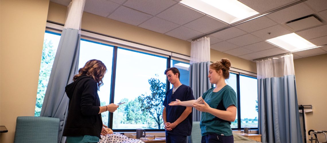 A group stands around a bed.